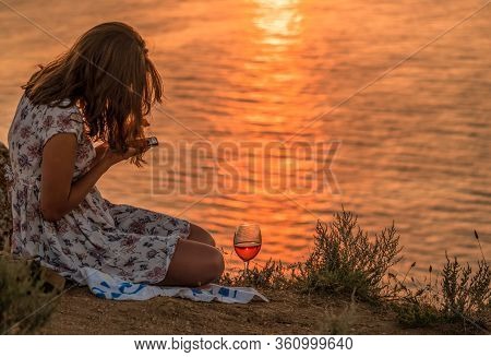 Girl Sitting With A Glass Of Wine At Sunset, A Young Woman Enjoying Evening