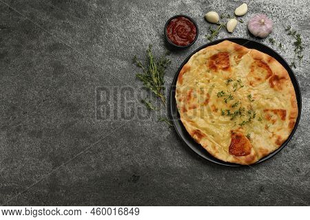 Delicious Khachapuri With Cheese, Thyme, Garlic And Sauce On Grey Table, Flat Lay. Space For Text