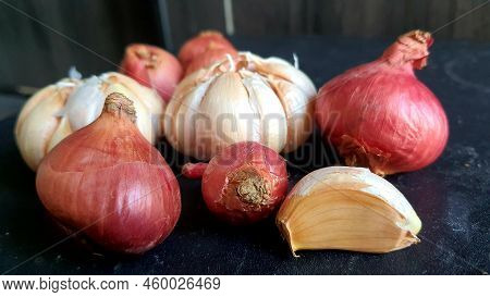 Bunch Of Onions And Garlic On A Black Table Board.