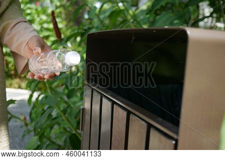 Women Hand Throwing An Empty Plastic Water Bottle In The Garbage Trash Or Bin