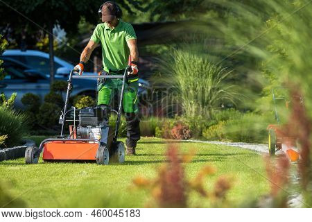 Landscaper With Scarifier Machine Taking Care Of A Lawn.. Removing Straw And Moss From A Grass Field
