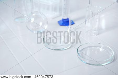 Glass Lab Dishes On White Table On The Background Of Labware Such As Beaker, Flask, Graduated Cylind