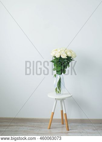 Beautiful Bouquet Of White Blooming Roses In Glass Vase On The White Wall Background. White Flowers 