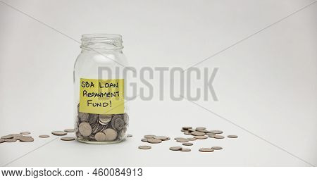 A Glass Jar Holds Many Quarters, Dimes And Nickels For An Sba Loan Repayment.