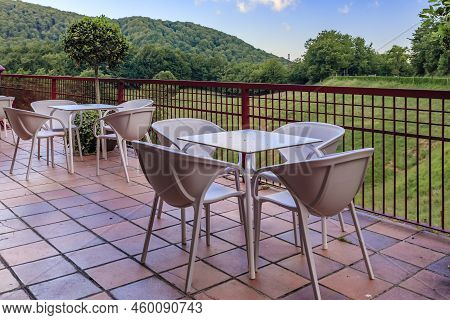 Table And Chairs At An Outdoor Cafe With A View Onto A Green Forest And Meadow In Ultzama, Spain