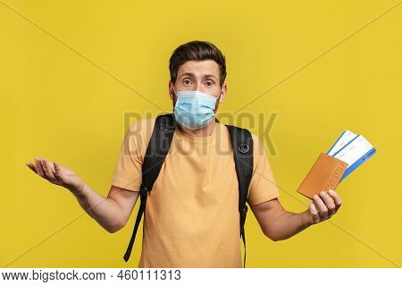 Cancelled Flight. Shocked Male Traveler Holding Travel Tickets And Speading Hands After Cancellation