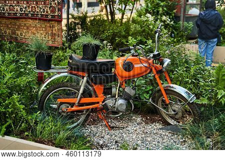 Moscow, Russia - 30.07.2022: A Soviet Orange Motorcycle Standing Among Green Plants
