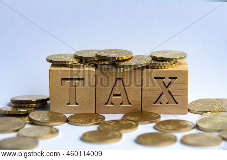 Tax Word Engraved On Wooden Block Surrounded With Gold Coins. Taxation Concept.