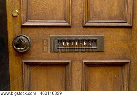 Close Up Of Brown High Quality Noble Wood Entrance Door With Brass Copper Metal Mail Slot And Inscri