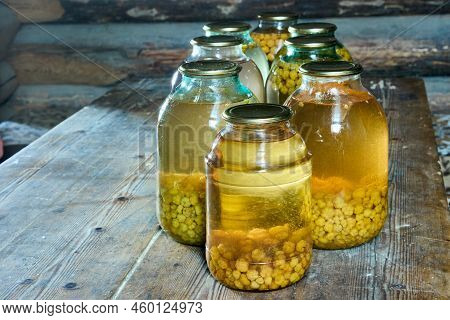 Homemade Canning Cloudberry Stewed Fruit In Large Jars On Table In Barn.