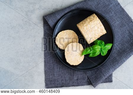 Top View Raw Tempeh Or Tempeh, Made Of Fermented Soybean Seeds. Tempeh Slices On Plate With Herbs. S