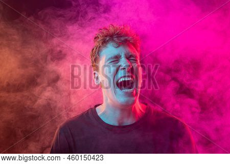 Shouting Excited Young Man With Bright Emotions Isolated Over Pink Background With Smoke. Concept Of