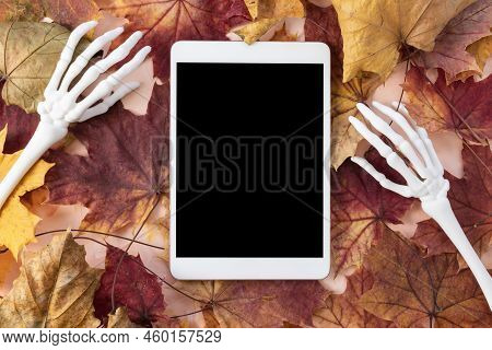 Digital Tablet Mock-up With Monster Skeleton Hands And Autumn Leaves Background. Happy Halloween, On