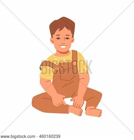 Smiling Toddler Sitting On Floor And Posing. Isolated Kiddo In Jumpsuit, Cute Personage. Childhood A