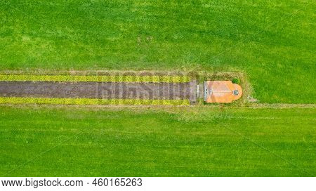 Garden Detail In Aerial View With Sand Path Going Between Two Hedges Towards A Little Building, A Sh
