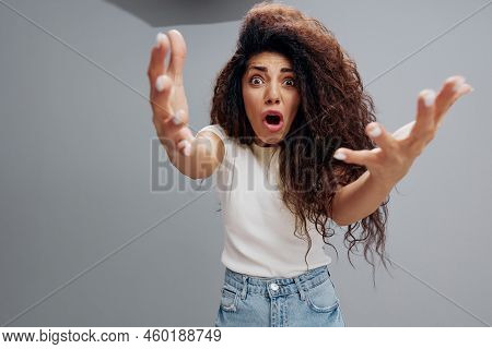 Wide Angle View Portrait Of Aggresive Shocked Screaming Young Latin Curly Woman In White T-shirt Loo