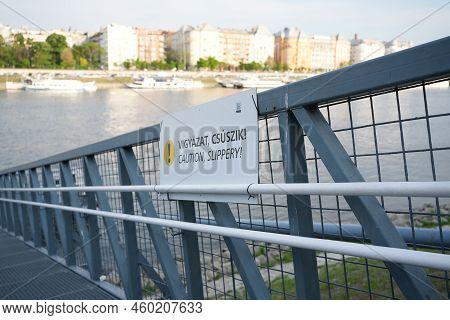 Bridge Leading Down To A River With A Sign