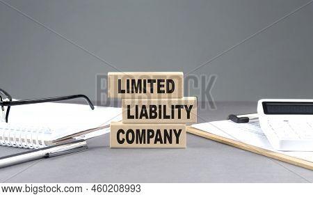Llc Limited Liability Company Text On A Wooden Block With Notebook,chart And Calculator, Grey Backgr
