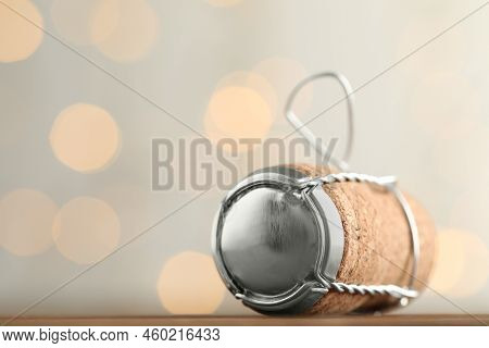 Sparkling Wine Cork With Muselet Cap On Table Against Blurred Festive Lights, Closeup. Space For Tex