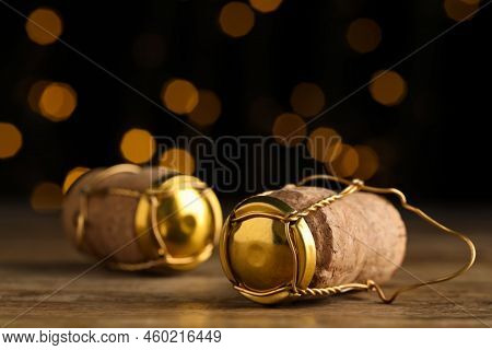 Corks Of Sparkling Wine And Muselet Caps On Wooden Table Against Blurred Festive Lights, Closeup. Bo