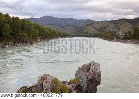 A Fast-flowing Wide And Full-flowing Mountain River. Large Rocks Stick Out Of The Water. Big Mountai