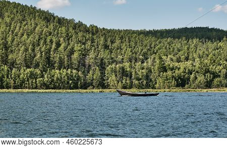 Man Floating On Fishing Wooden Longboat With Motor Along Western Wooded Shore Of Chivyrkuisky Bay Of