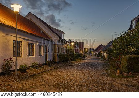 An Uneven Cobbled Street Illuminated By Streetlamps And The Sunset In The West, Mariager, Denmark, A