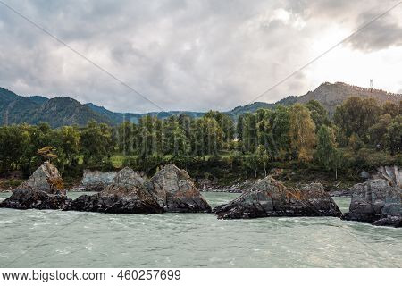 A Fast-flowing Wide And Full-flowing Mountain River. Large Rocks Stick Out Of The Water. Big Mountai