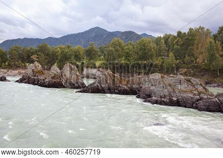 A Fast-flowing Wide And Full-flowing Mountain River. Large Rocks Stick Out Of The Water. Big Mountai