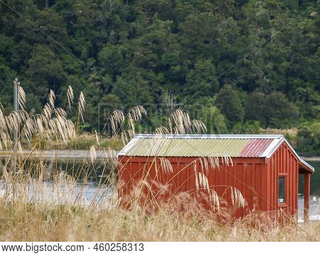 Red Trampers Hut In New Zealand Bush Beside River Or Lake Waikareomoana.