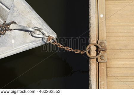 Top View Of The Nose Of The Metal Boat Chained To The Dock With Rusted Chain