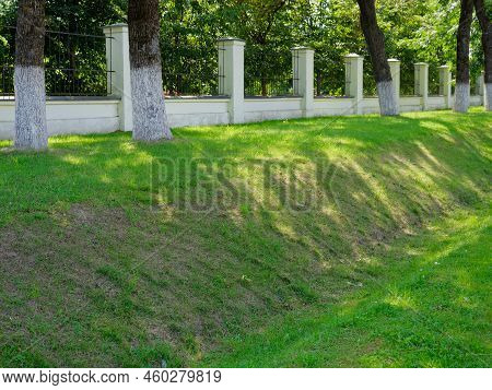 Brick Fence With A Lawn Around A Green Park