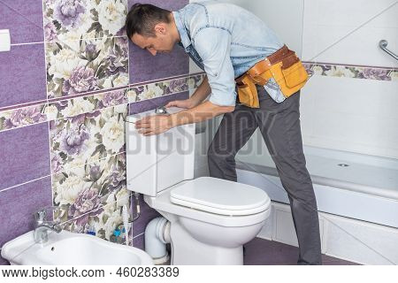 Plumber Fixing Water Hose On Toilet Cistern