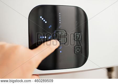 Hand Lowering The Temperature Of Hot Water In Electric Water Heater To Save Energy
