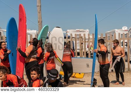Aveiro, Portugal - August 19, 2022: People With Wetsuits And Pick Up Surfboards At The Secreto Surf 
