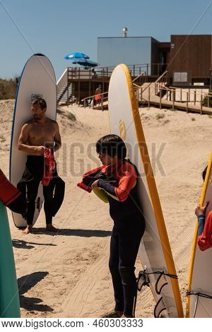 Aveiro, Portugal - August 19, 2022: People With Wetsuits And Pick Up Surfboards At The Secreto Surf 