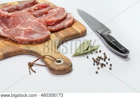 Sliced Fresh Meat And A Knife On A Cutting Board. - сomposition With Bay Leaf And Black Pepper