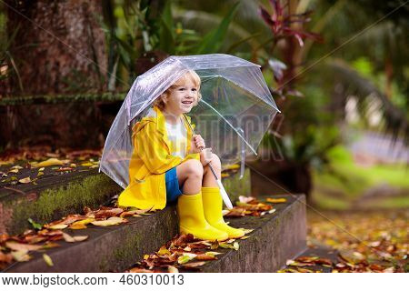 Child Playing In Autumn Rain. Kid With Umbrella. Little Boy Running In A Park In Fall Season. Outdoo