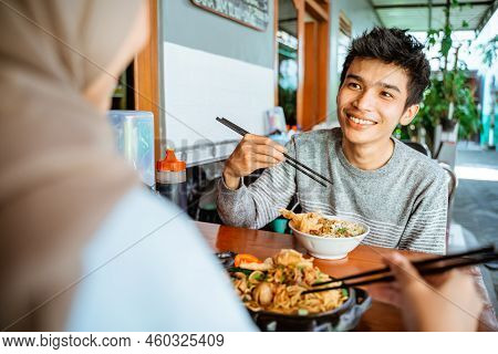 Close Up Of Male Customer Holding Chopsticks Enjoying Chicken Noodles