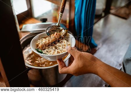 Close Up Of Sellers Hand Put Chicken On Noodles