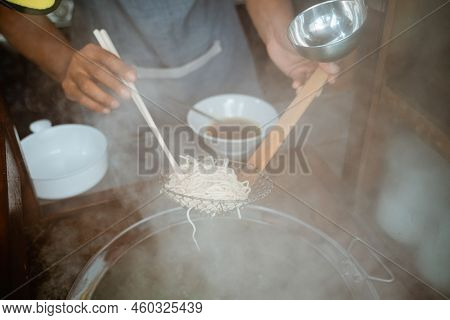 Hands Drain Boiled Noodles With A Sieve And Chopsticks