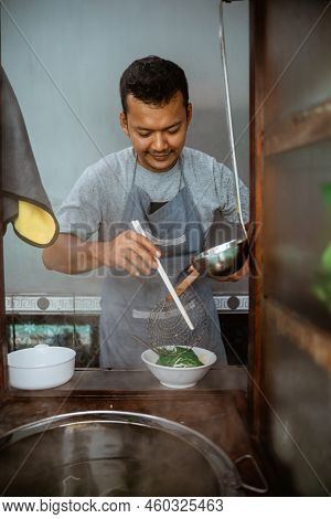 Man Seller Stirring Boiled Noodles With Chopsticks In A Bowl