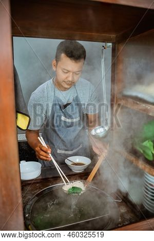Man Seller Draining Boiled Noodles With A Drainer And Chopsticks