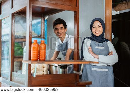 Veiled Woman Wearing Apron With Hands Crossed And Young Man