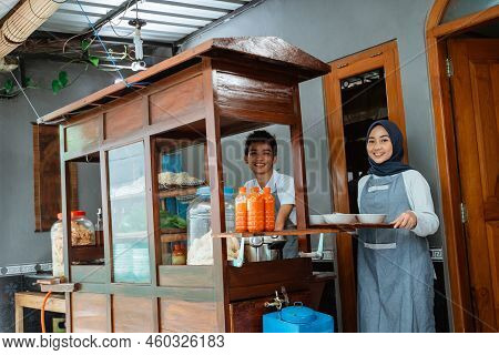 Smiling Two Sellers In Apron Preparing Chicken Noodles Dish
