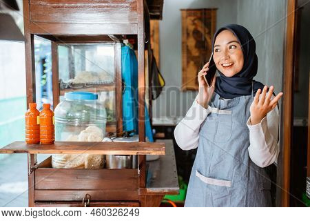 Veiled Woman Wearing An Apron Talking On A Cellphone