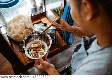 Man Seller Put Chicken Topping Over Noodles In A Bowl