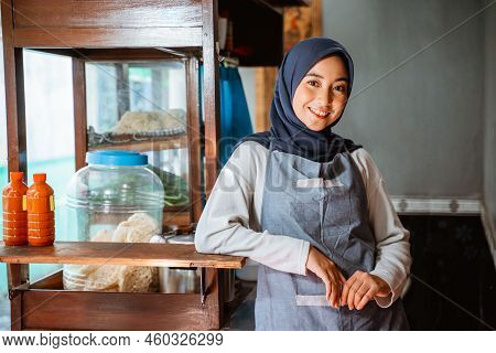 Asian Hijab Woman Wearing Apron Smiling While Standing Beside Cart