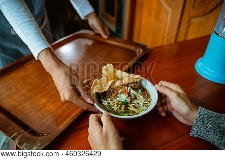 Waiters Hand Serving A Bowl Of Chicken Noodle Dish