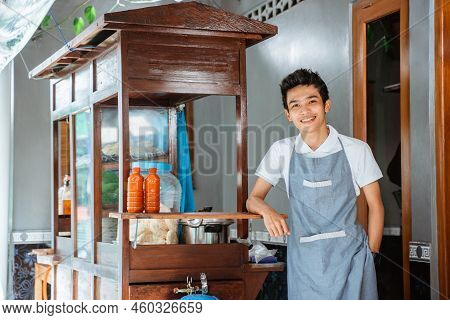 Smiling Man Selling Standing Next To A Cart